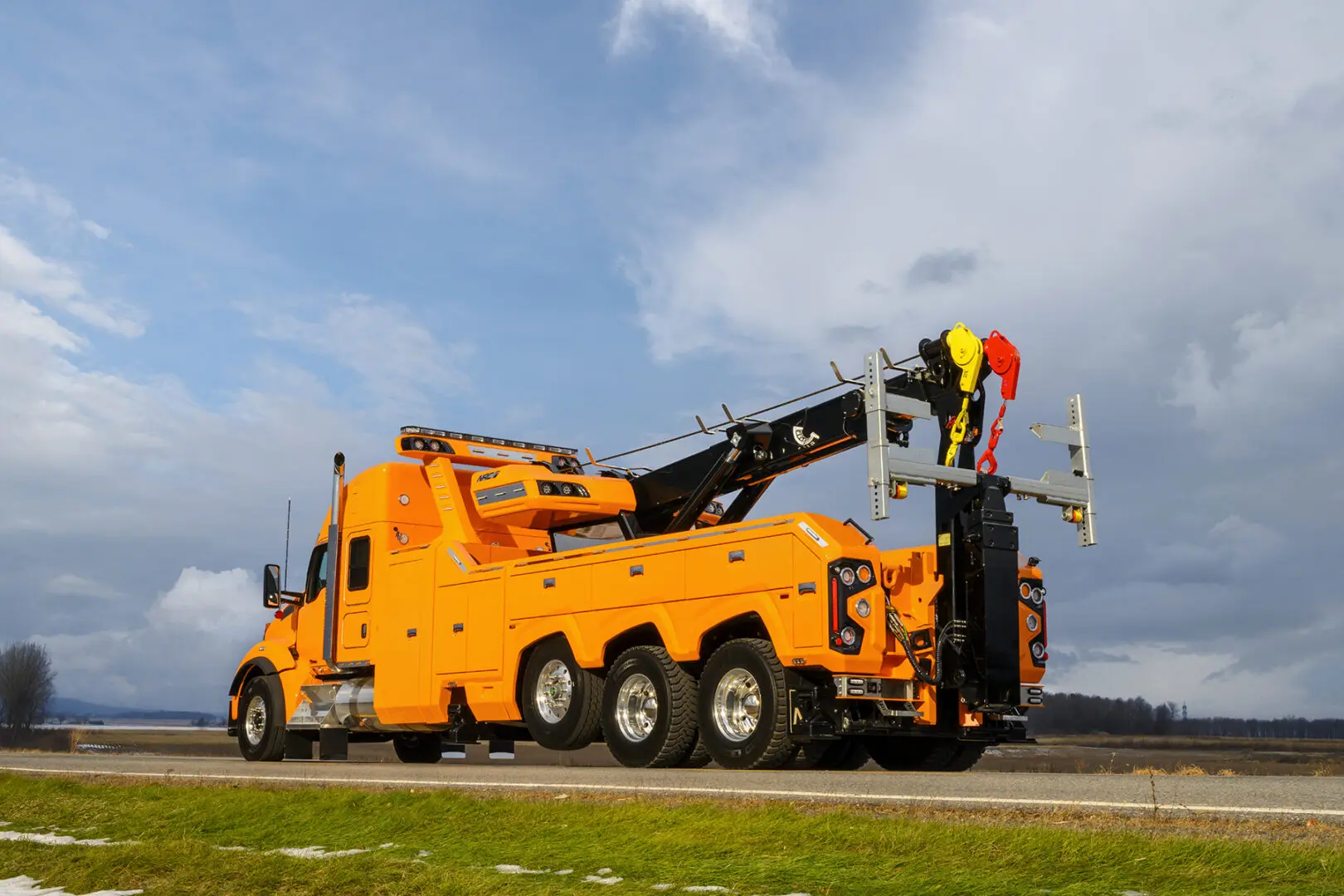 Orange tow truck on a rural road.