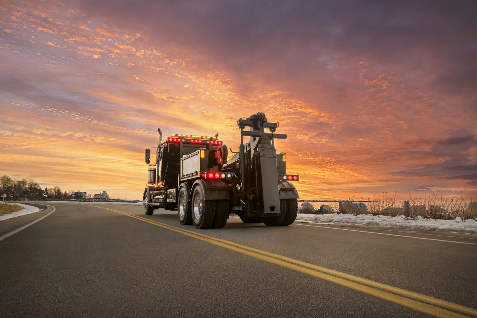 Tow truck on road at sunset.
