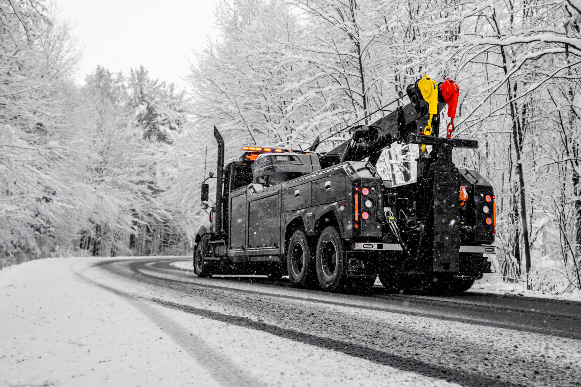 Tow truck on snowy forest road.