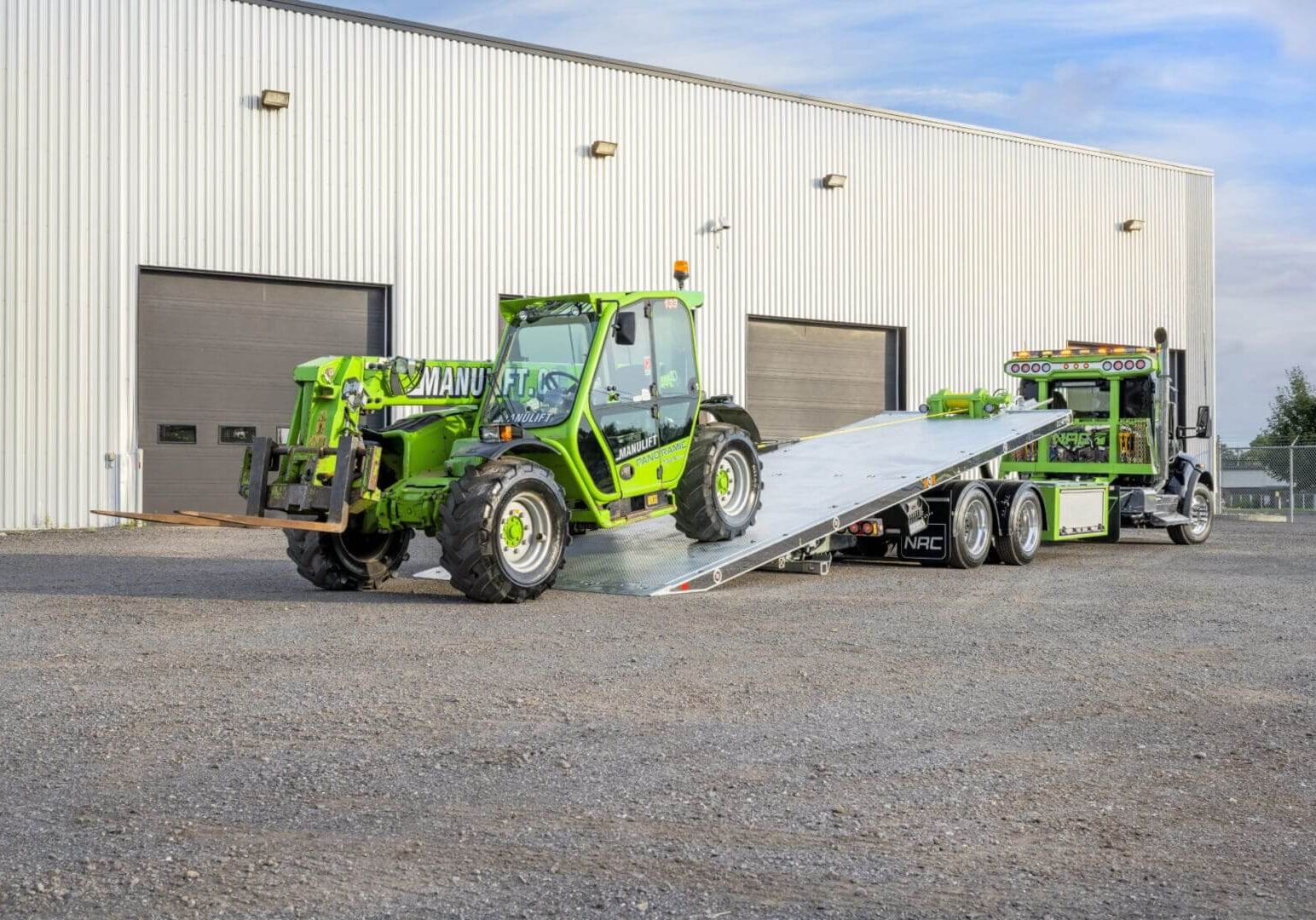 Green vehicle being loaded onto a truck.